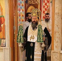 The solemn scene of the Holy Hierarchal Liturgy in the Church of the Transfiguration of the Lord, celebrated by Metropolitan Justin of Žička in a luxurious golden vestment, surrounded by clergy and faithful in prayerful silence in front of the rich iconostasis.