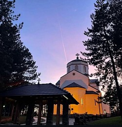 Night shot of the Church of the Transfiguration illuminated by decorative lighting as snowflakes fall on the stone facade and bell tower